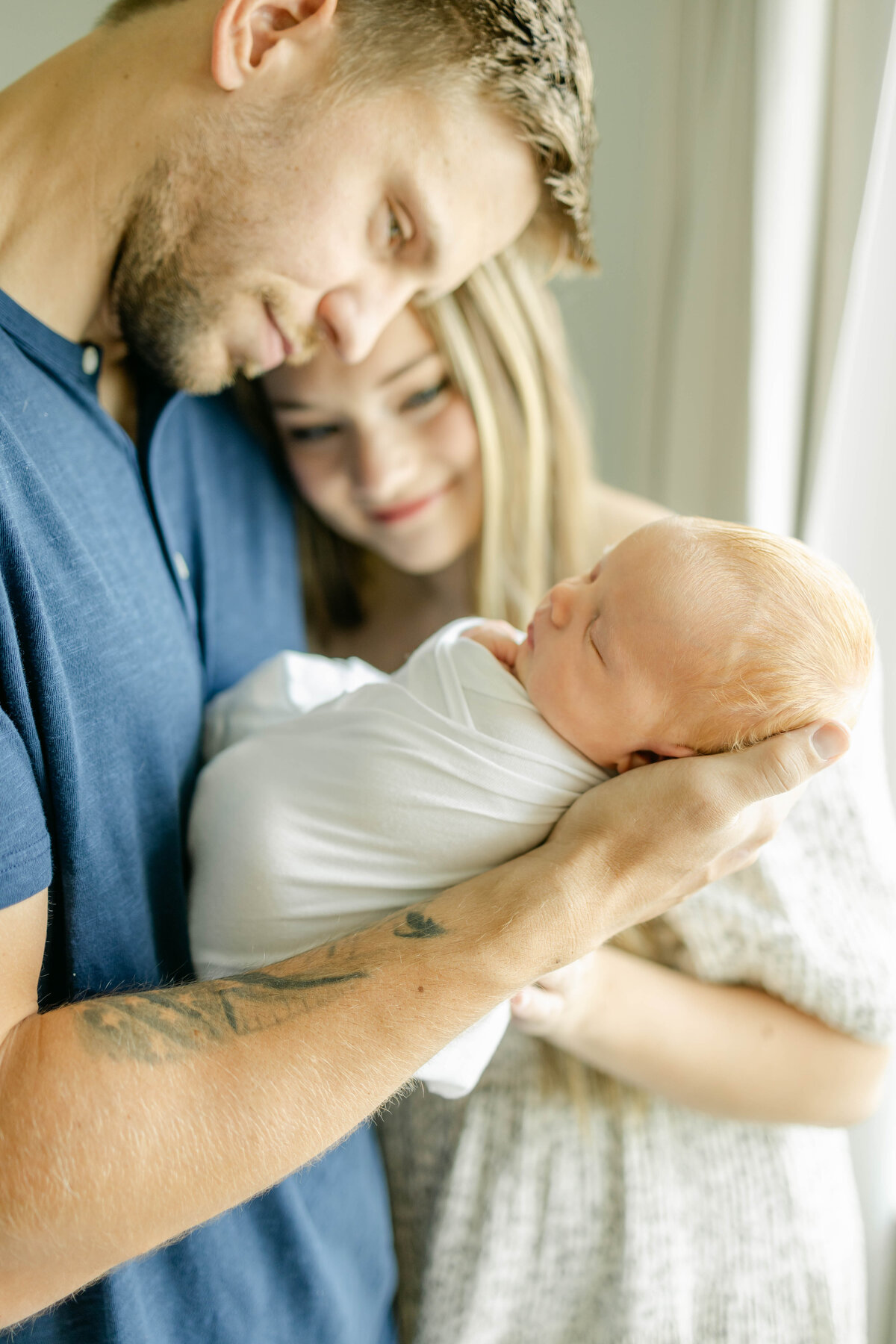 a couple looking at their newborn baby while his dad holds him up at their home in frisco texas