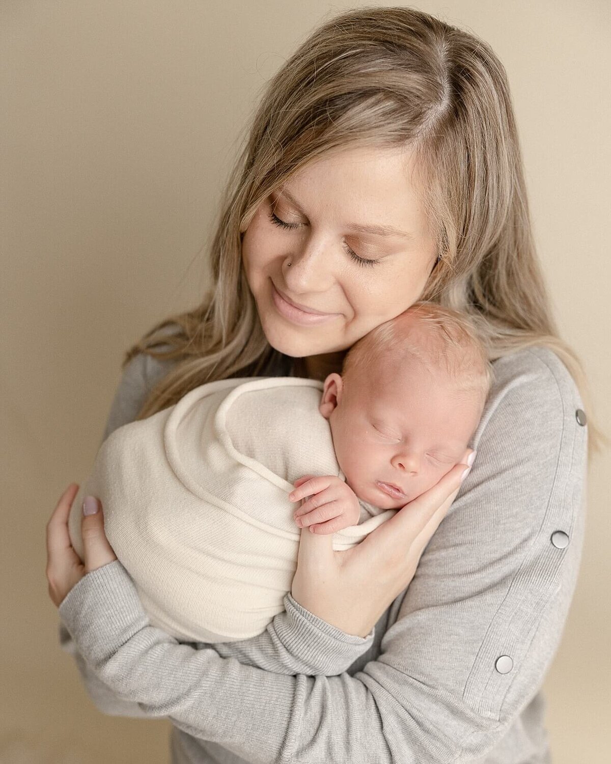 mom in grey sweater holding wrapped baby boy for photos