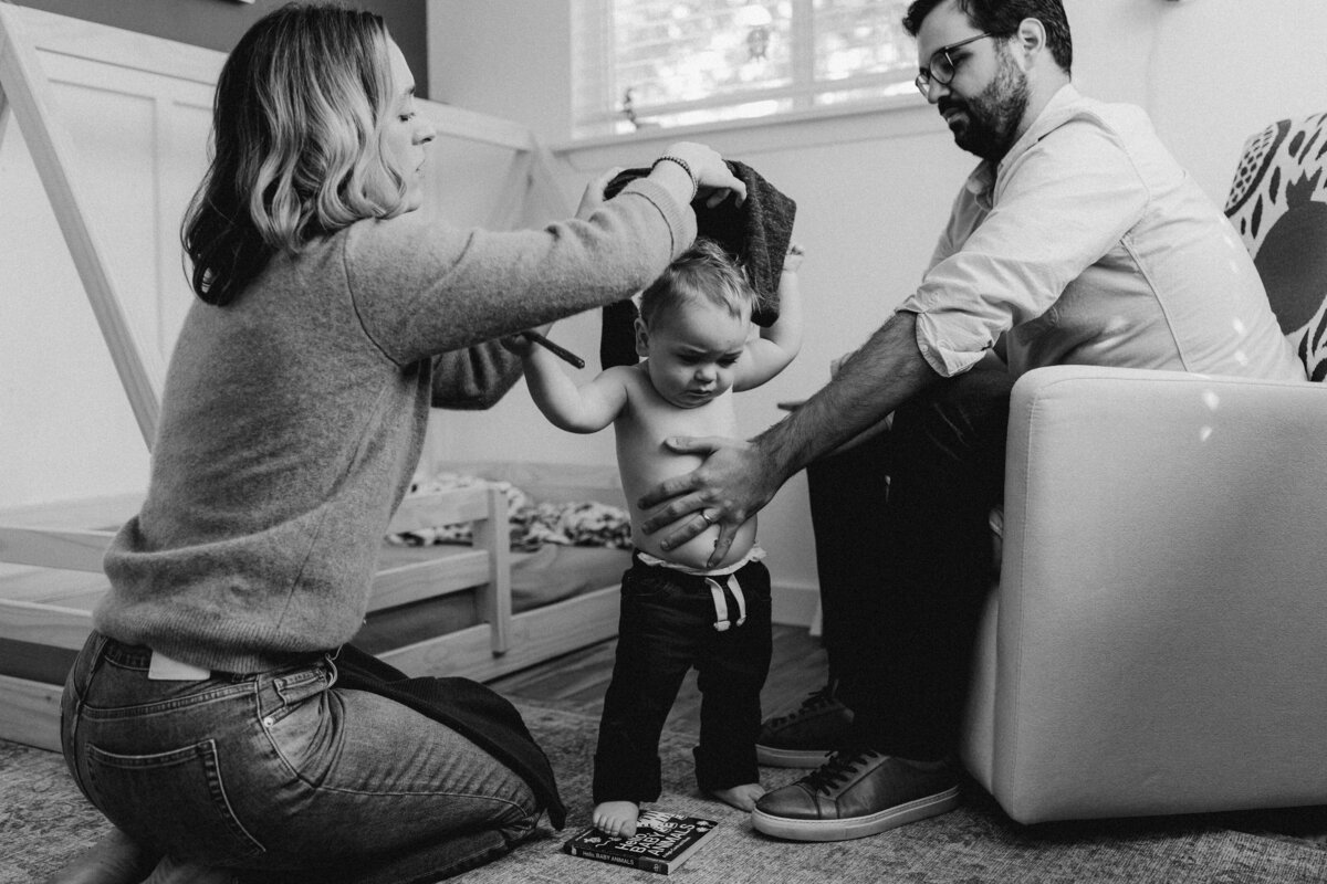 Mother and father getting toddler dressed at Austin family photo session