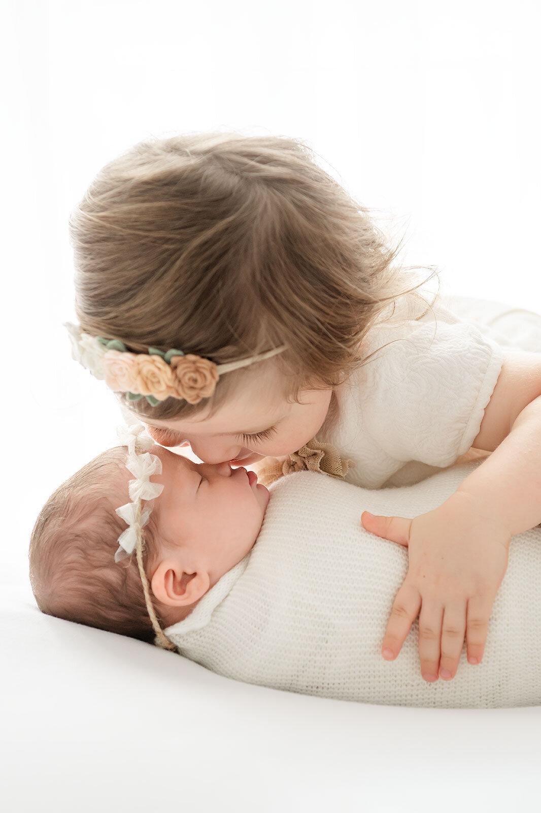 a little girl kissing her newborn sister