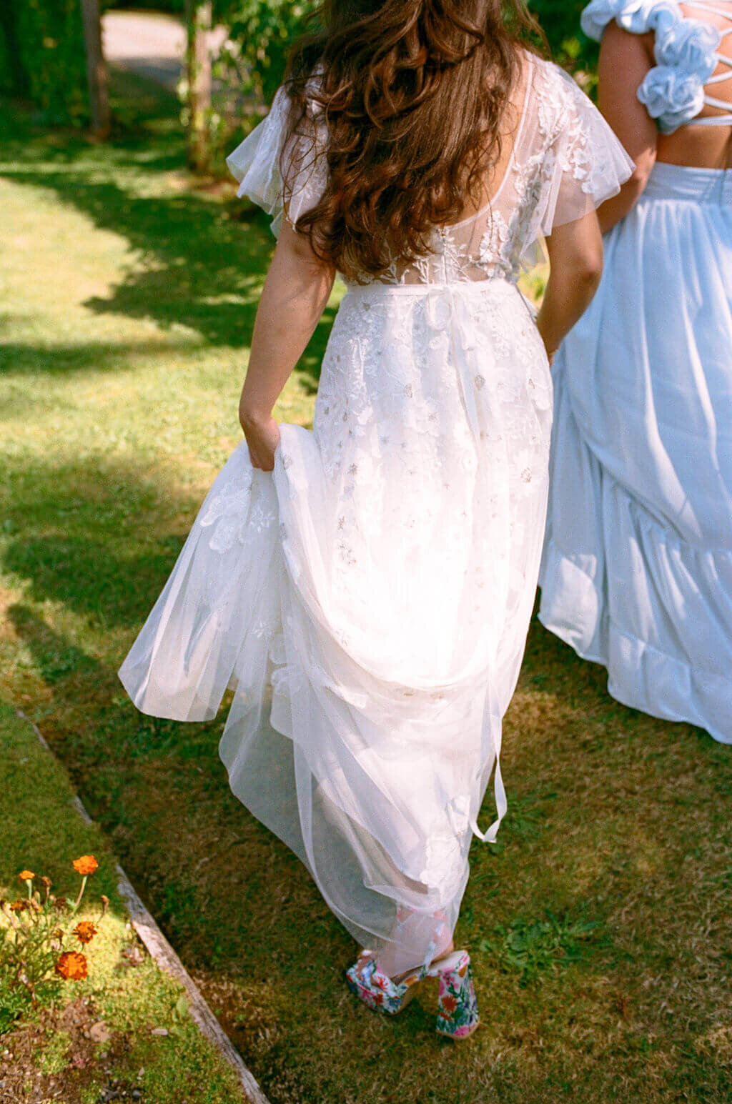 A bride hold up her wedding dress at her outdoor garden wedding.