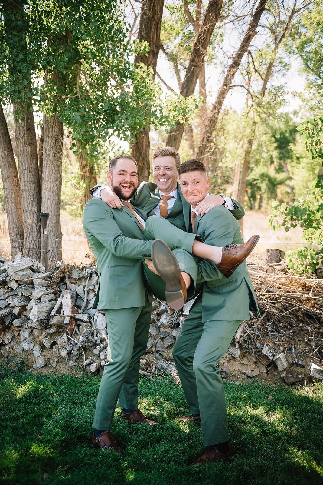 Groom poses with his groomsmen all in green suits.