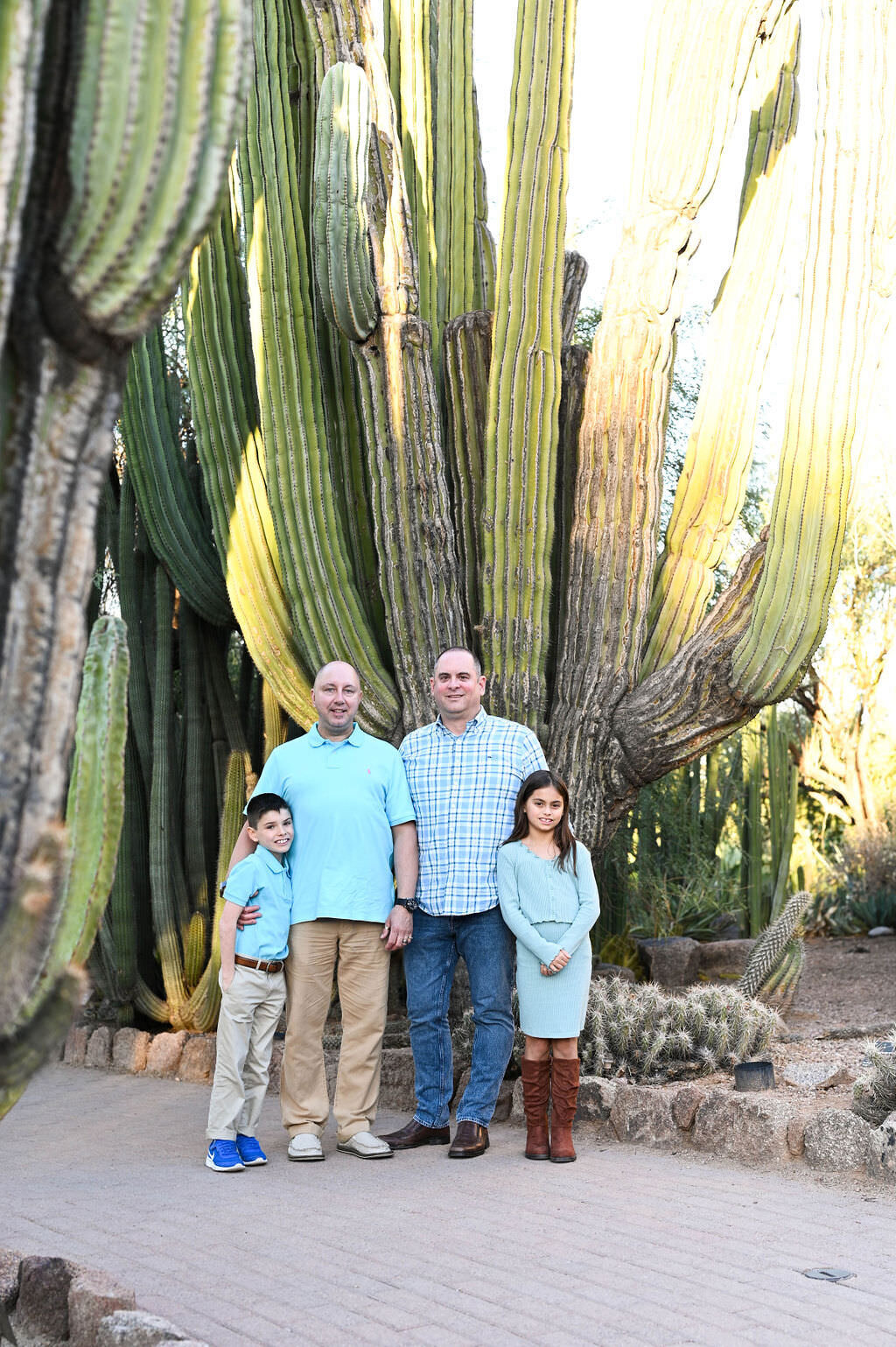 Parents standing with their kids in front of a large cactus