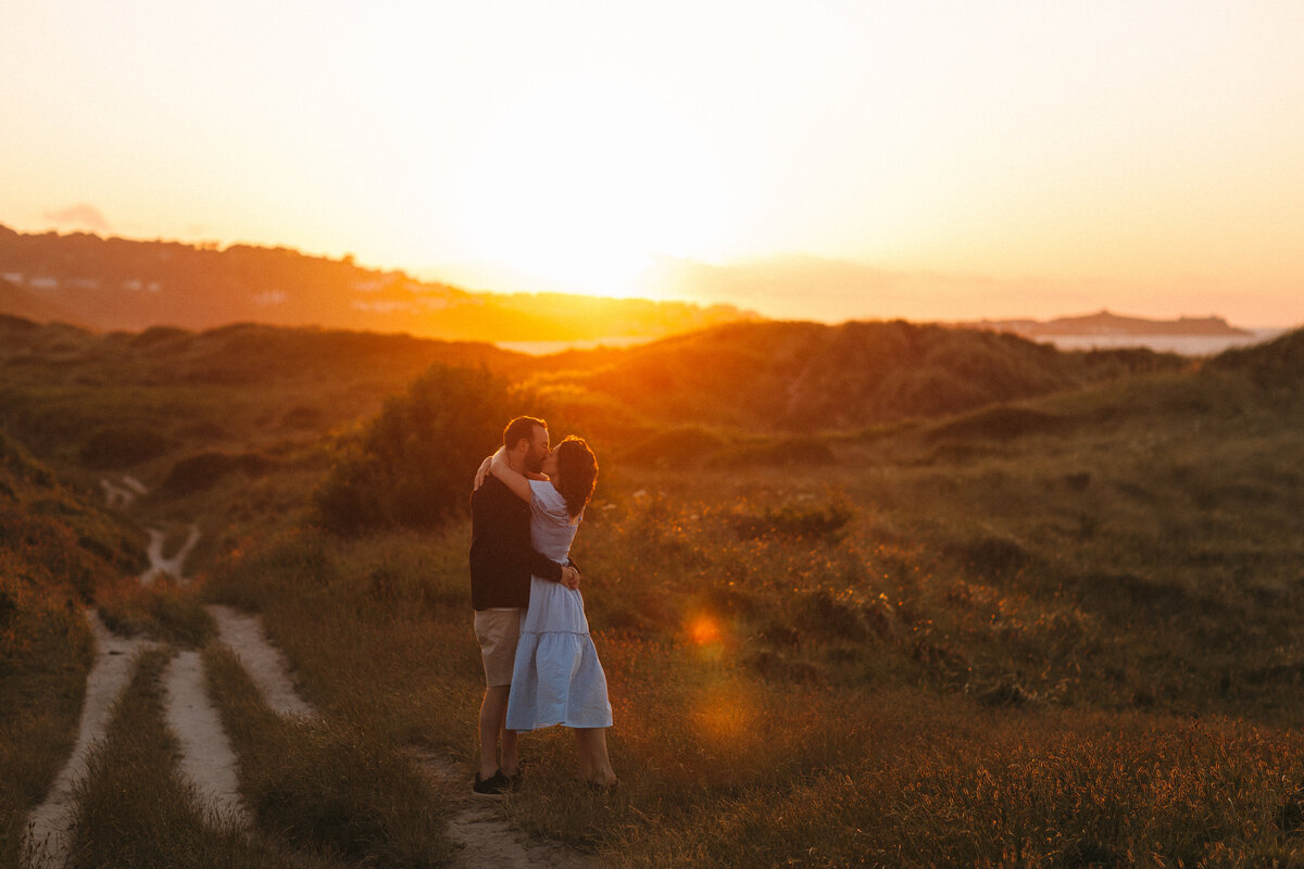 Couple Kiss as sun sets over the dunes near St Ives
