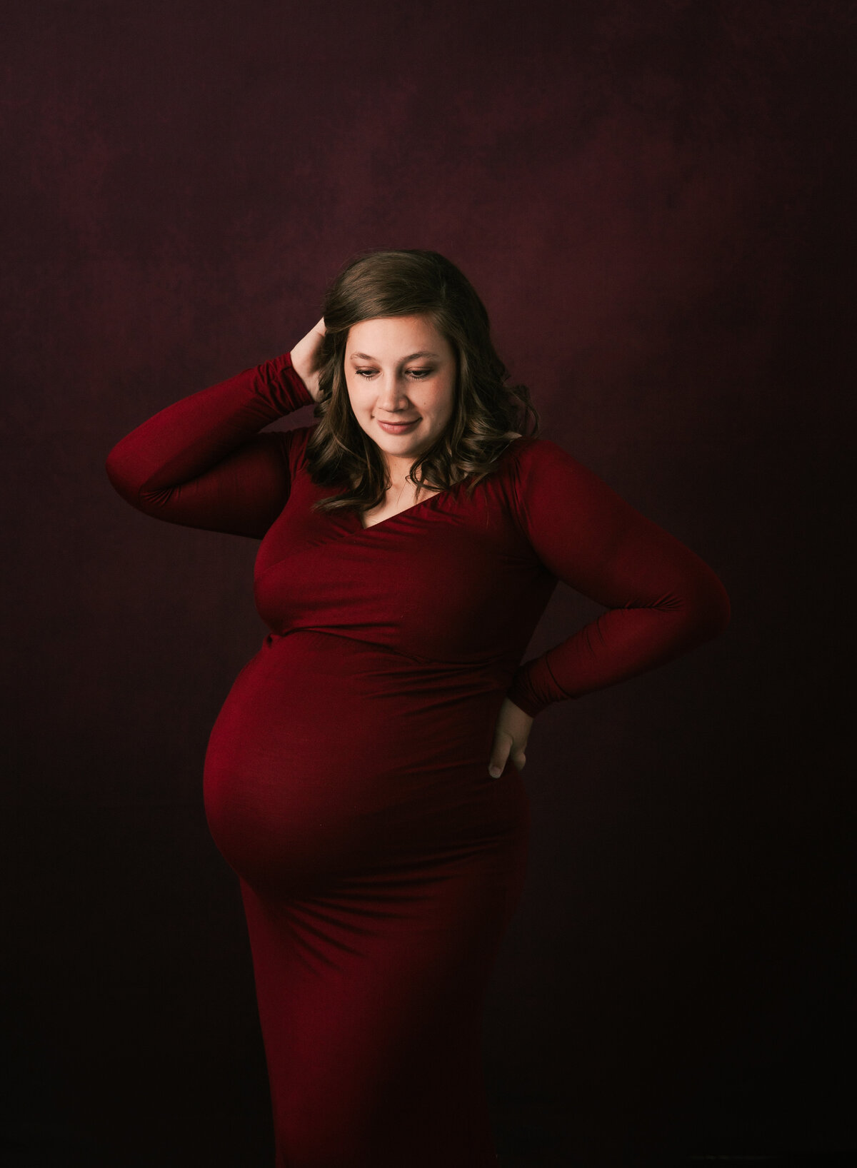 A beautiful pregnant mom brushes her hair back in her studio portrait by Diane Owen.