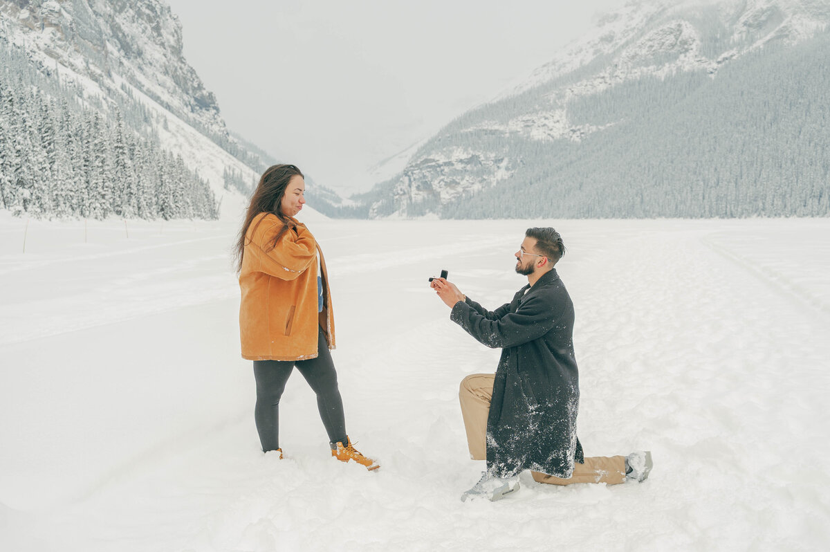Man proposing to his partner in the middle of snowy Lake Louise.