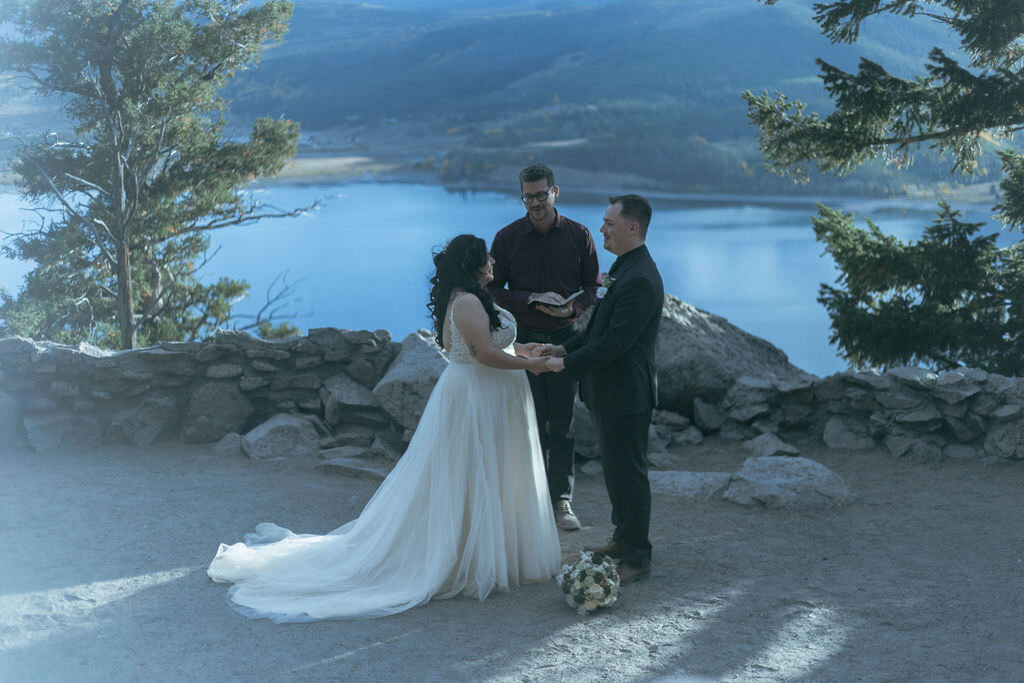 A couple holding hands during their mountain wedding ceremony.