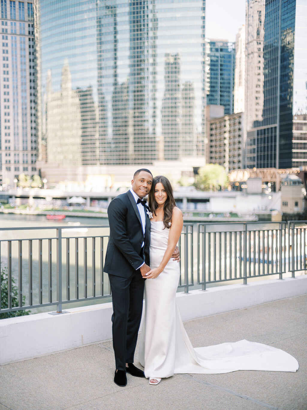 The newlyweds pose together by the Chicago River, dressed in classic wedding attire.