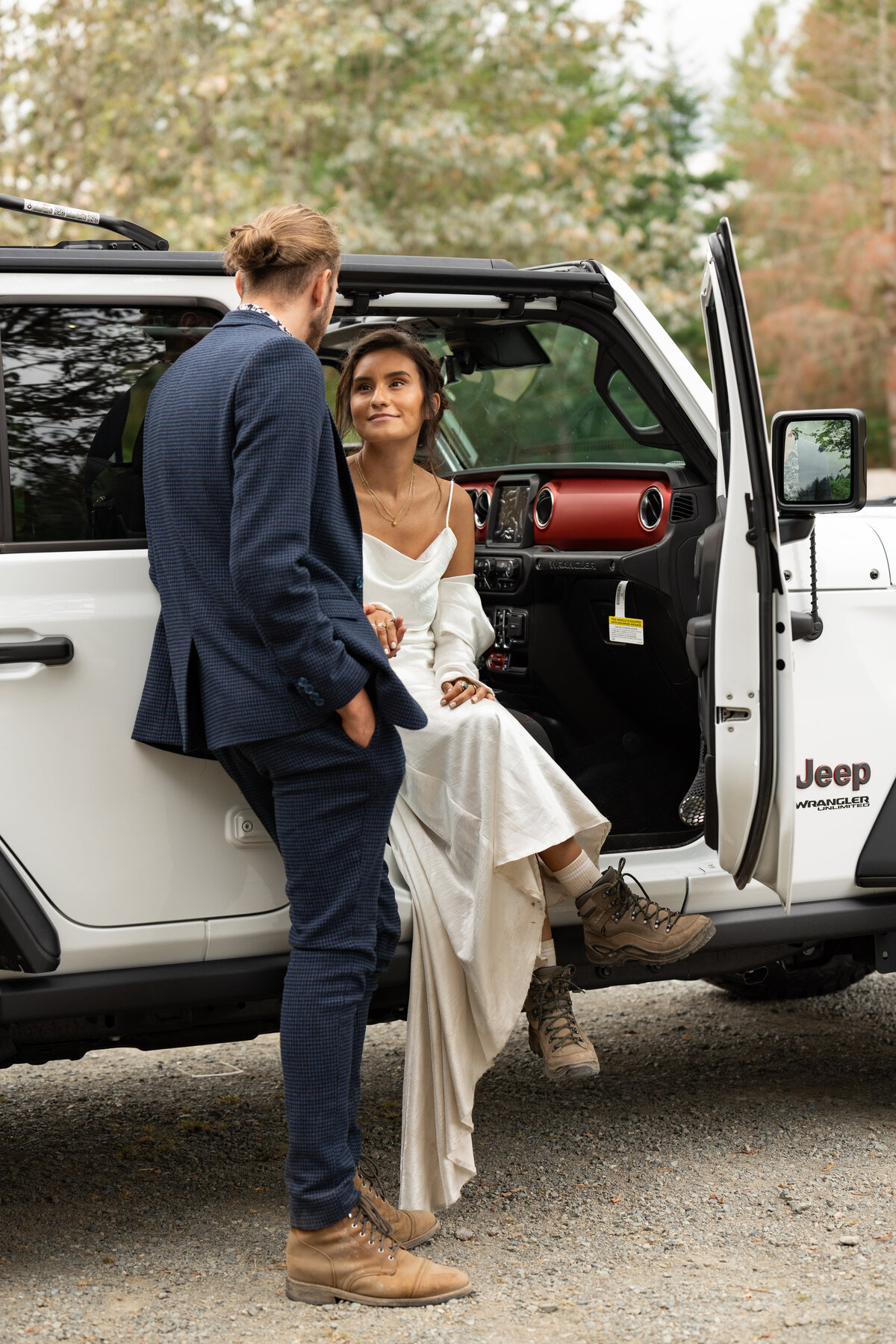 A person sitting in a car with the door open looking at her partner