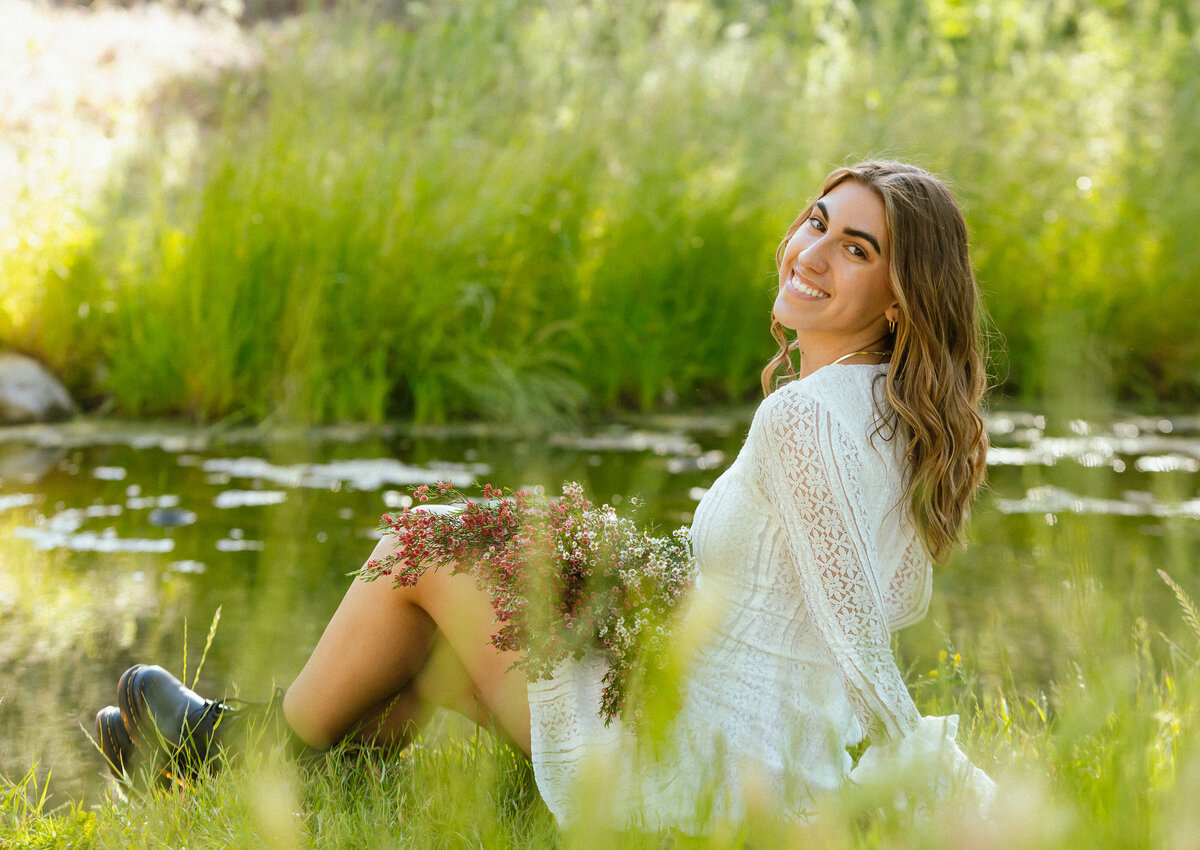 woman sitting on the ground by a lake