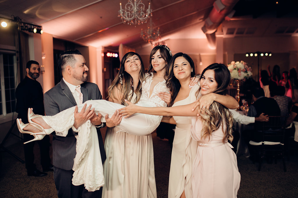 Wedding Photograph Of Women In Dresses And Man In Suit Carrying The Bride Los Angeles