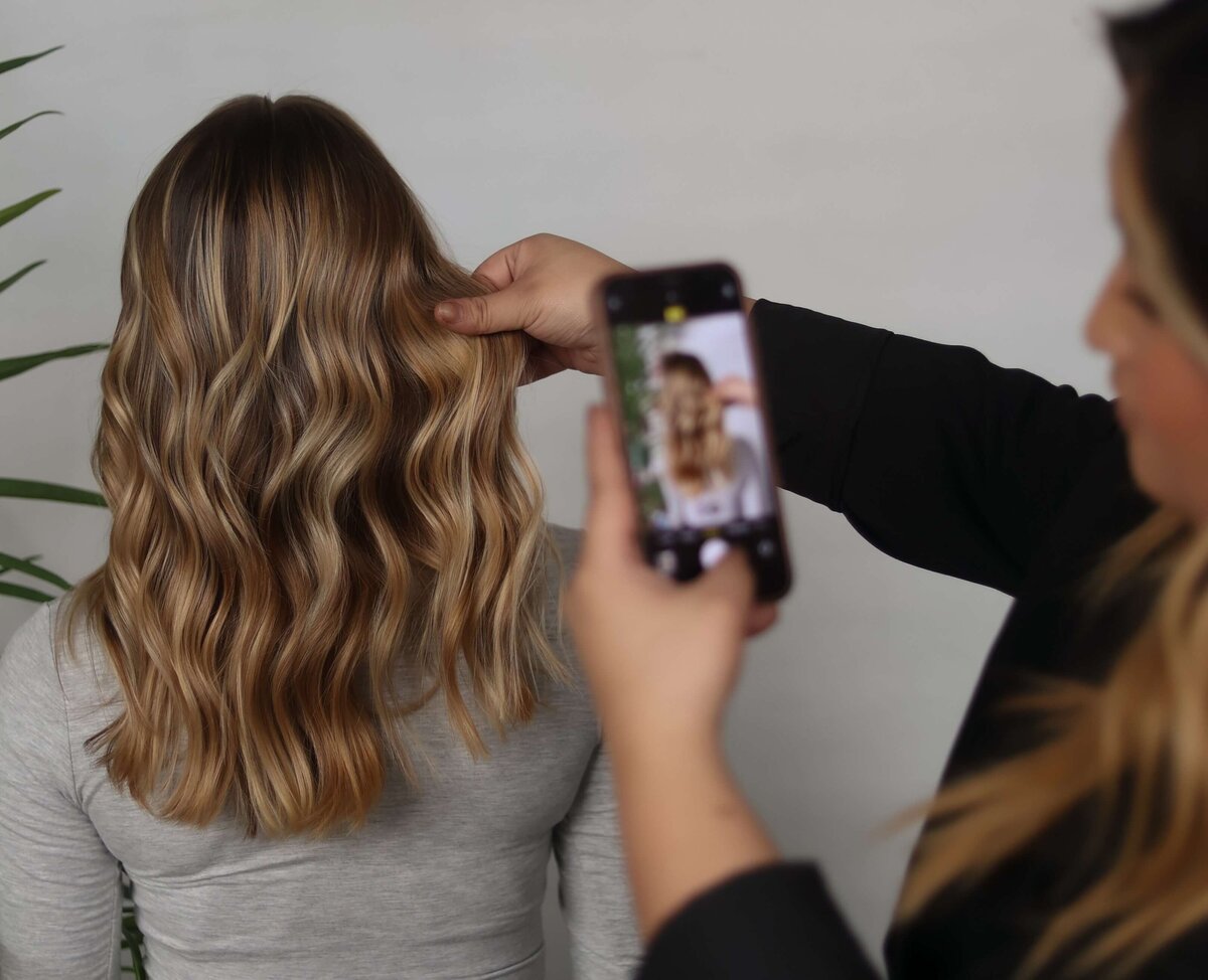stylist taking a picture of woman's hair styled at beauty salon in cedar rapids, iowa