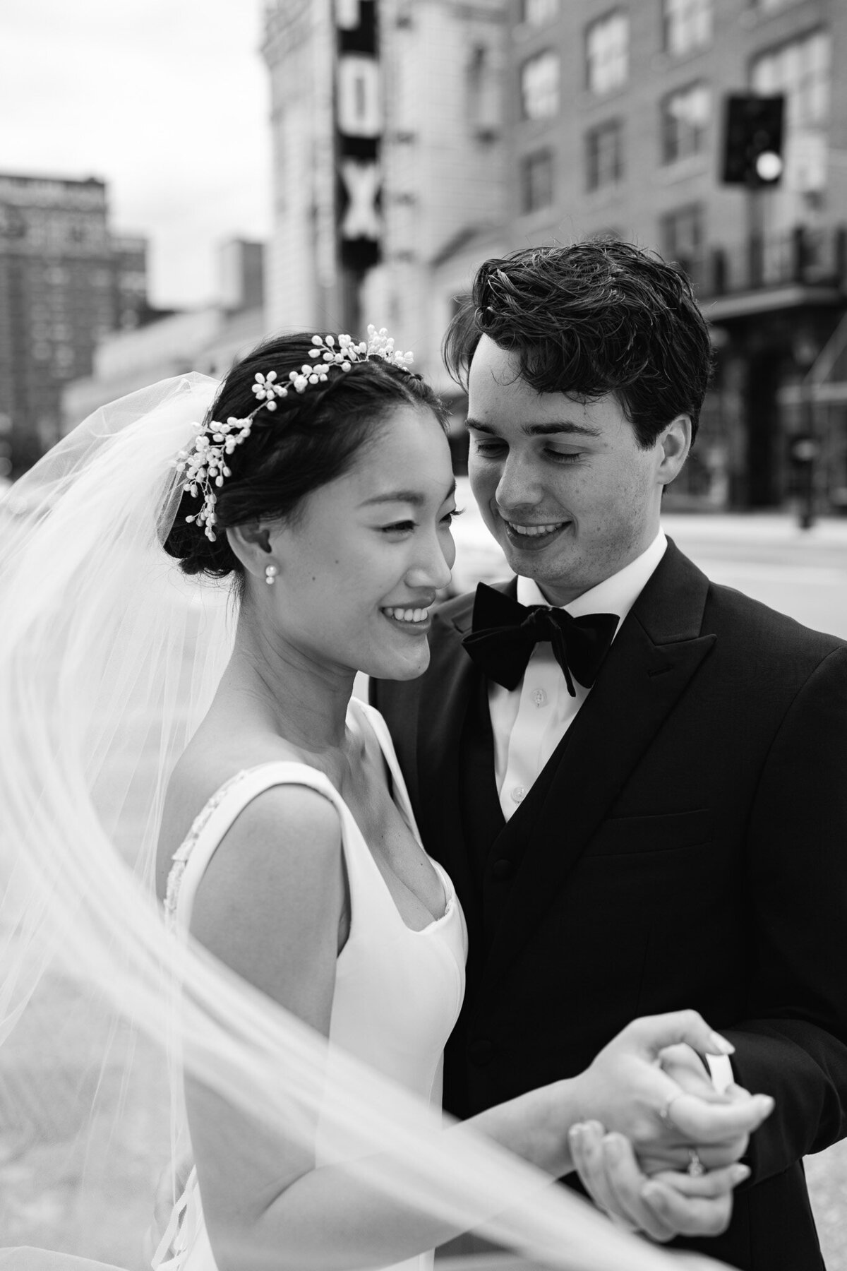 black and white photo of bride and groom smiling and holding hands