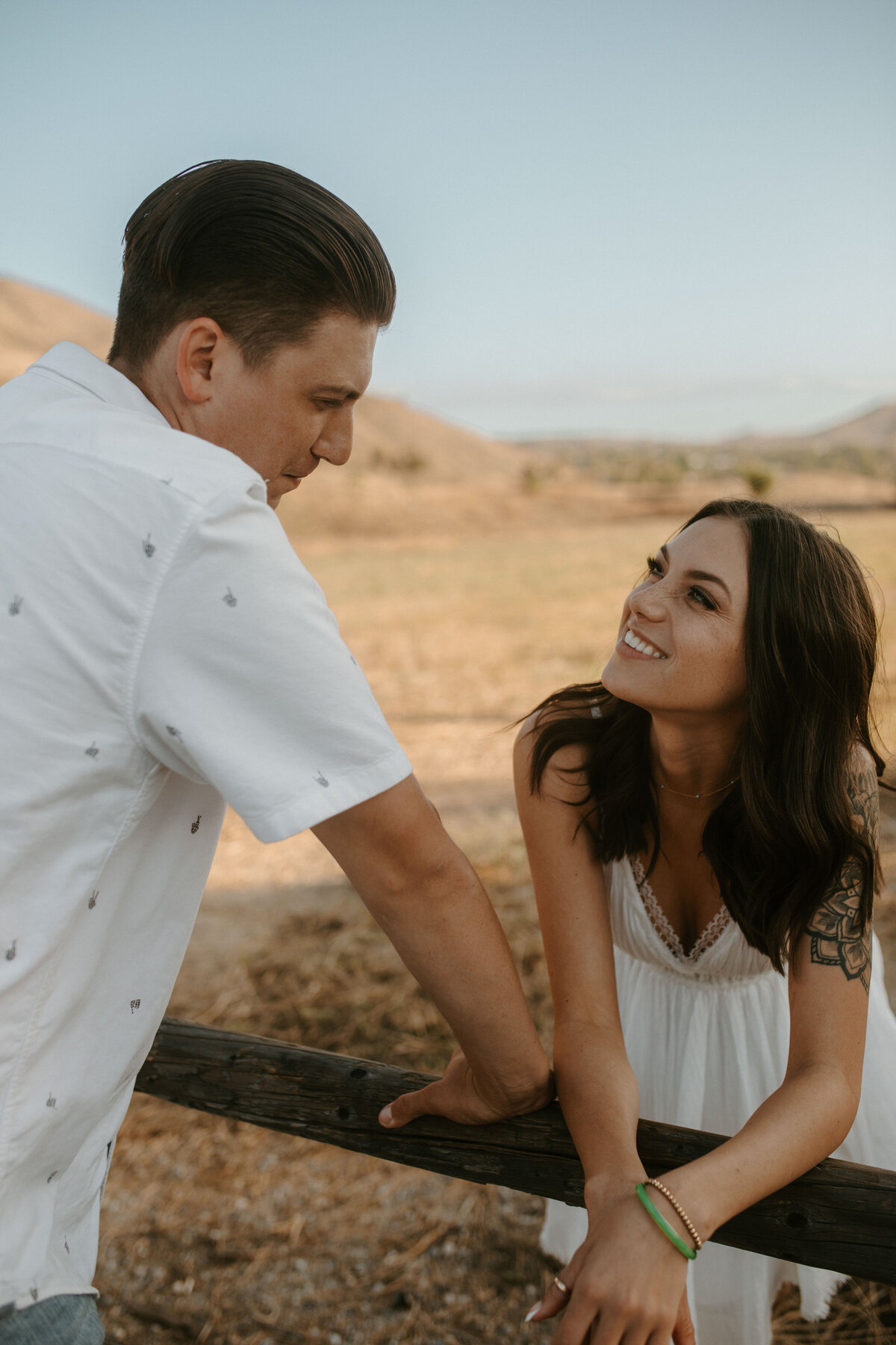 couple looking at each other lovingly in filed with picket fence