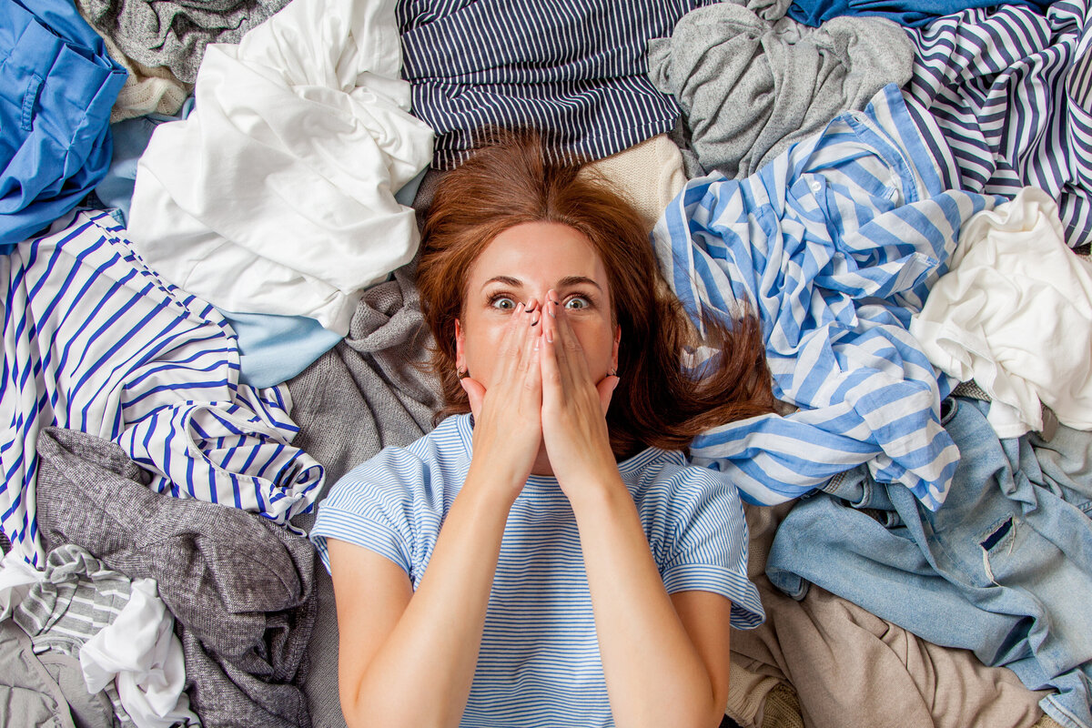 woman surrounded by clothes decluttering