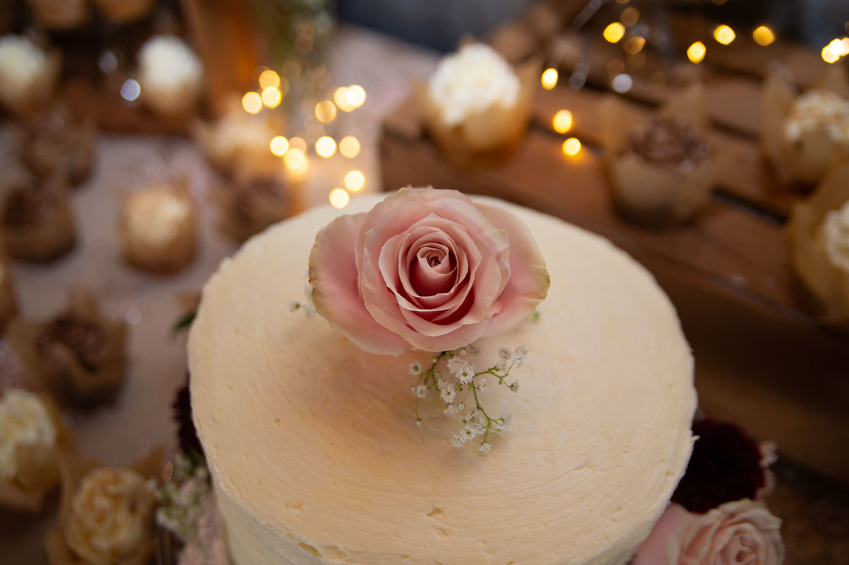 single pink rose atop cream  wedding cake