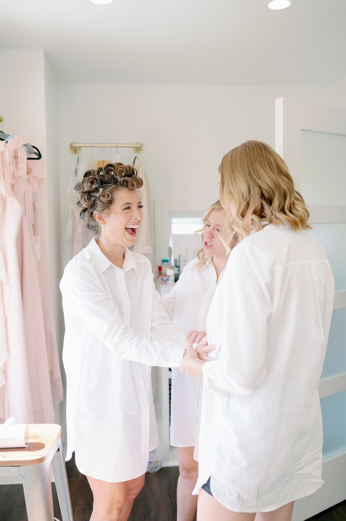 a bride laughing with bridesmaids while getting ready for her wedding
