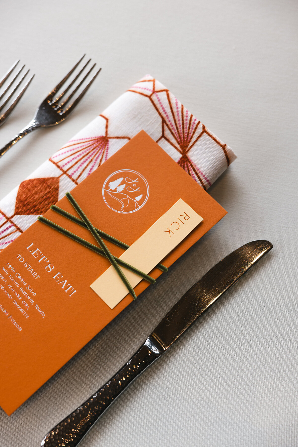 custom calligraphy wedding menu on a printed cloth napkin with florals and flatware representing full service design and calligraphy by Life in Letters.