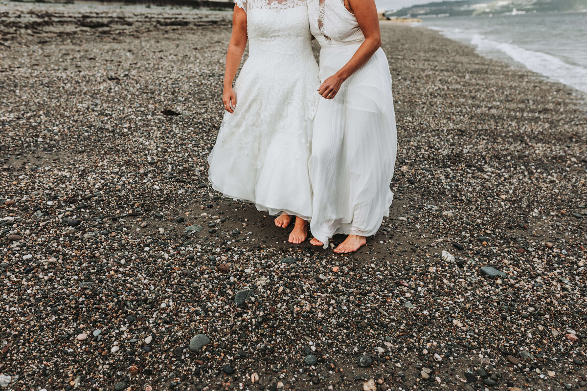 two brides walking on the beach