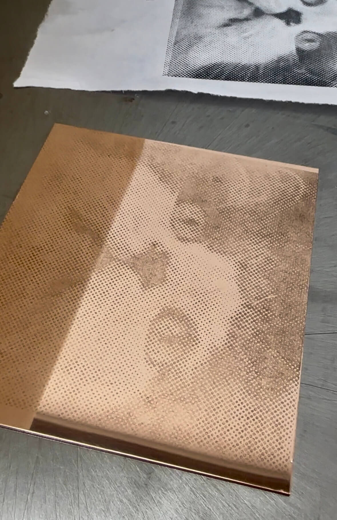 A close-up of a copper plate etched with a halftone dot pattern image of a cat using toner transfer.