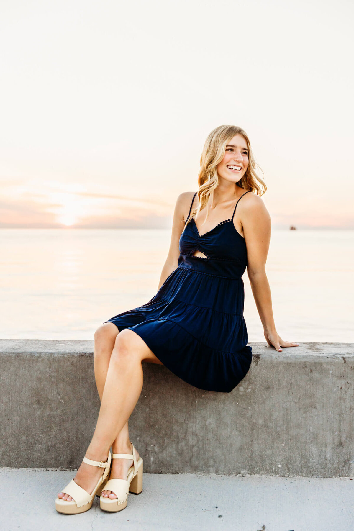 senior girl  in a blue dress smiling over her shoulder at the sister bay marina