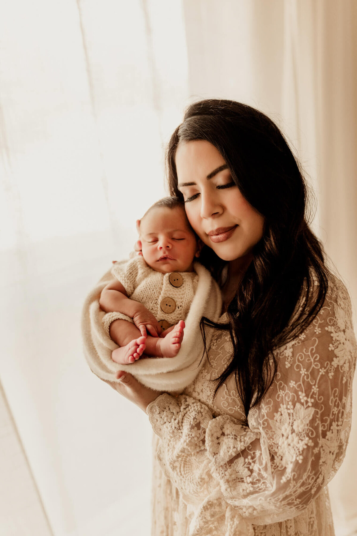 Mother with dcark brown hair holds her baby boy next to her cheek, Yukon studio session.