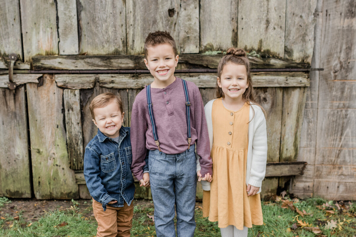 three siblings holding hands and cheesing