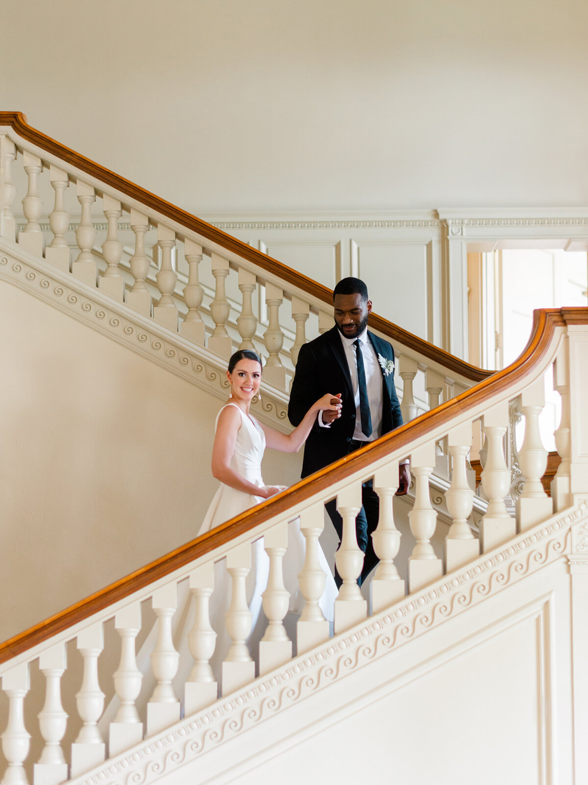 Elegant bride and groom descend the grand staircase of Cairnwood Estate during a refined wedding editorial, captured by Philadelphia Fine Art Wedding Photographer Elizabeth Kane. The architectural details and timeless styling evoke classic East Coast sophistication and luxury estate wedding charm.