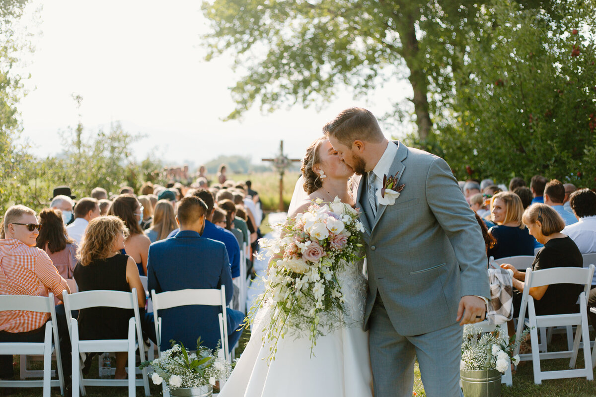 A bride and groom kiss at the end of the aisle after their wedding in Fort Collins, Colorado.