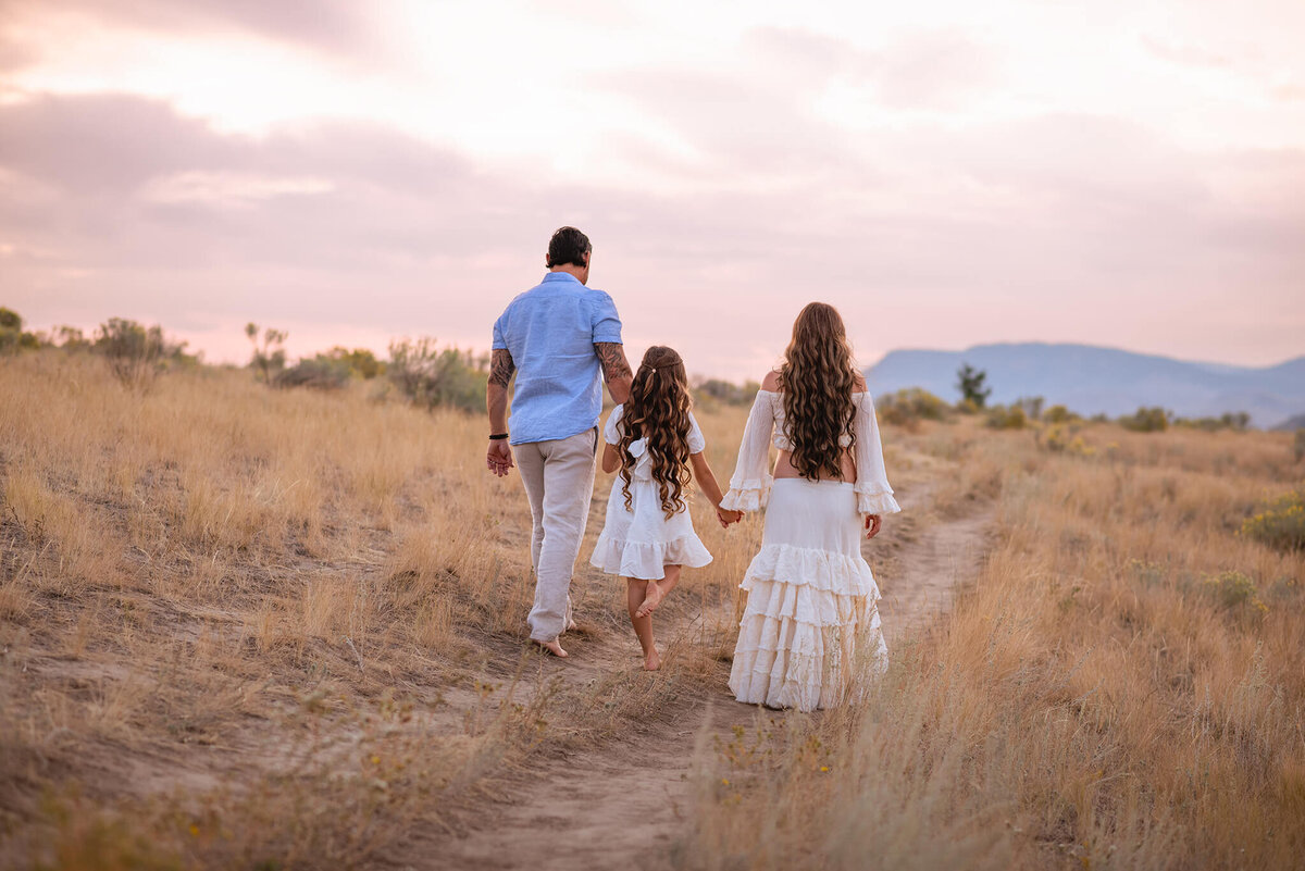 A family of 3 walk away from the camera with the sunset in behind them. Brittany Danielle captures this in Kamloops,BC