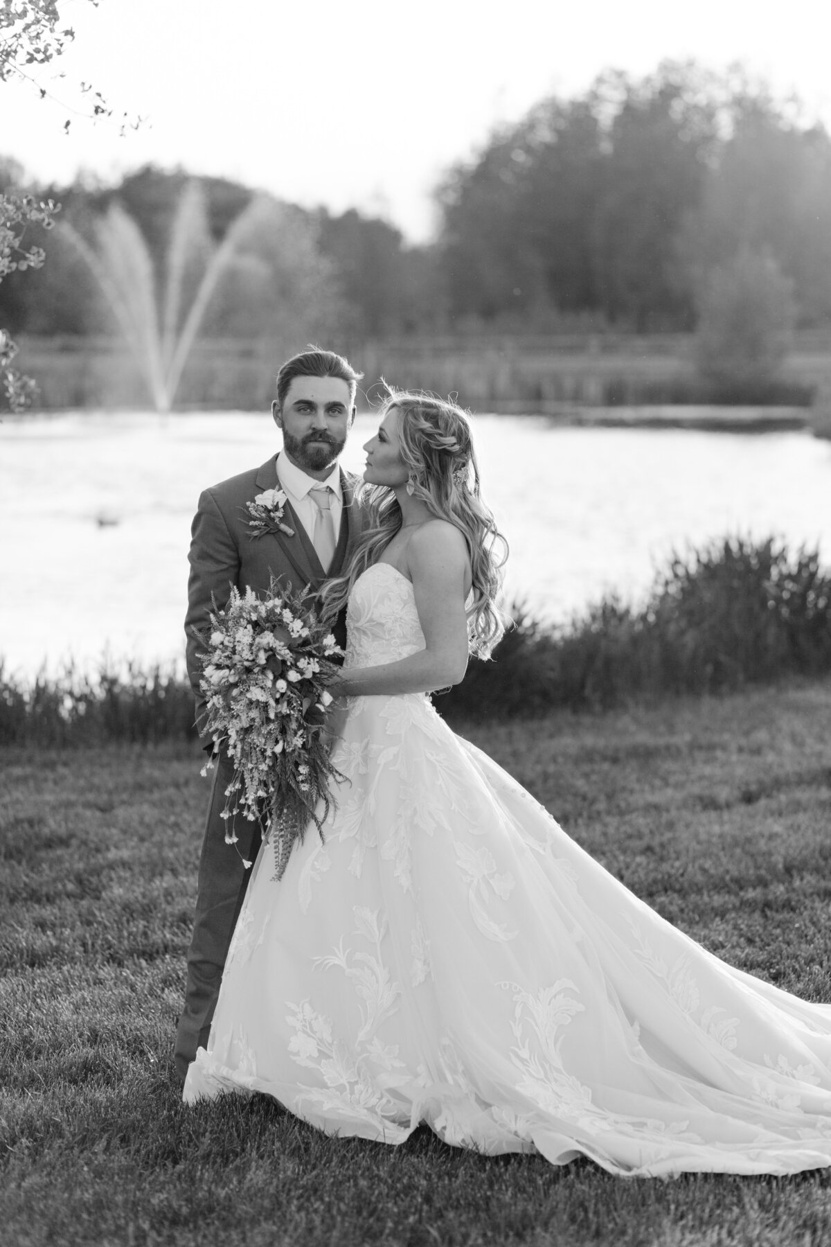 black and white image bride and groom posing by lake