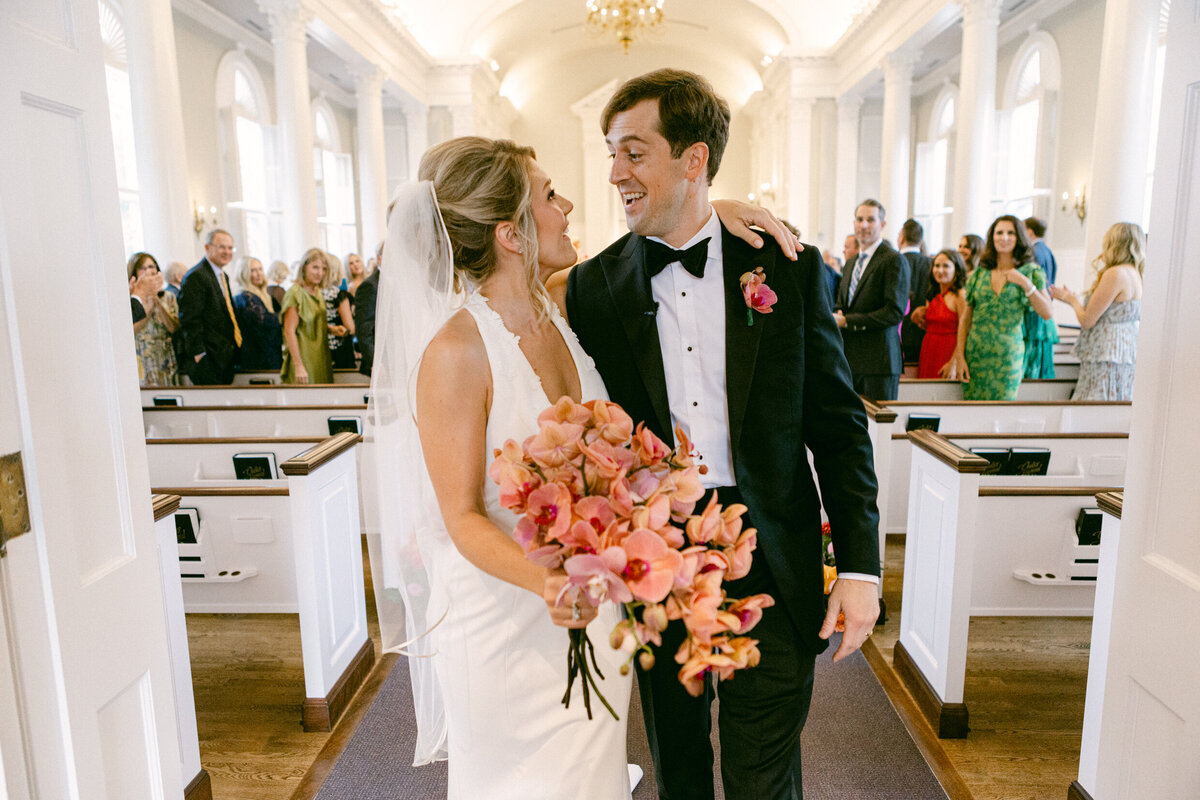 A wedding day photo of the bride and groom after walking down the aisle after they got married