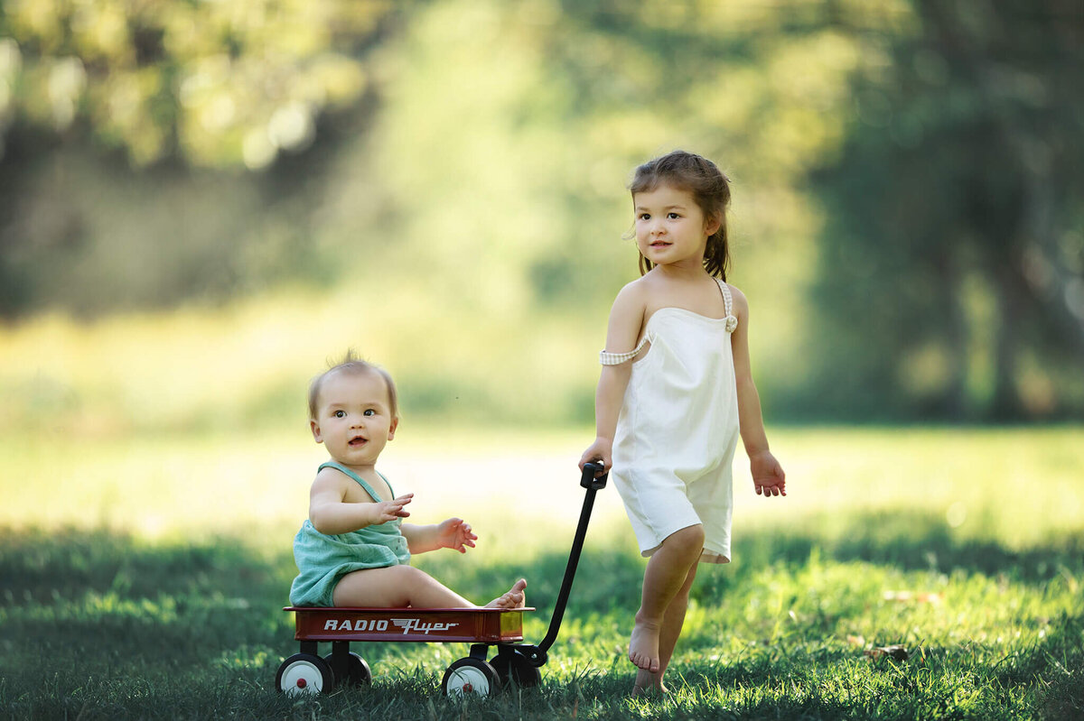 Sister pulling baby brother in a wagon