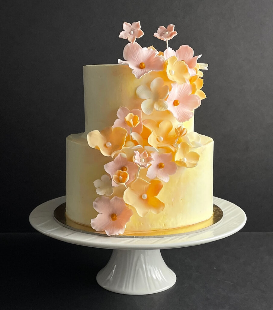 Fun spring-inspired yellow coloured two-tiered textured wedding cake, with pink and tangerine cascading sugar roses, created by Chartier YYC, elegant cakes & desserts in Calgary, AB, featured on the Brontë Bride Vendor Guide.