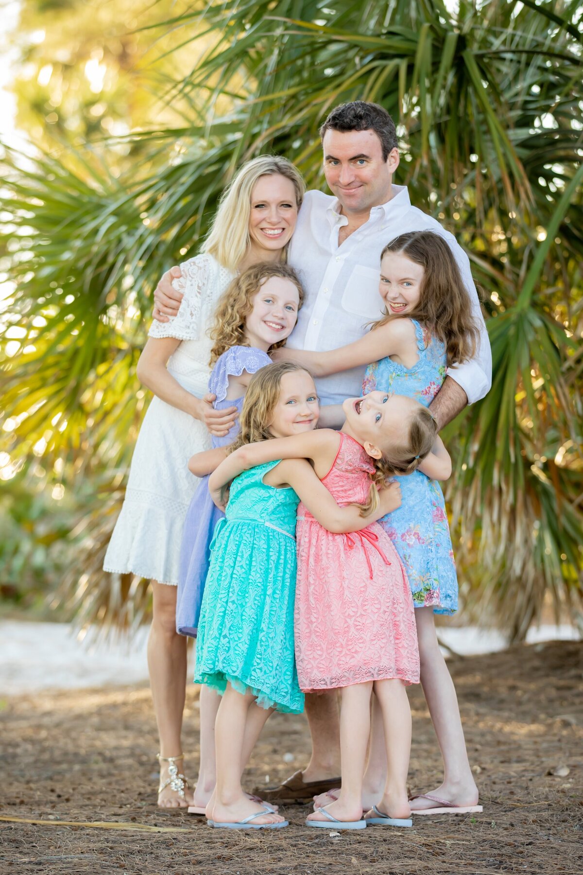 Family of five with three daughters hugging dad