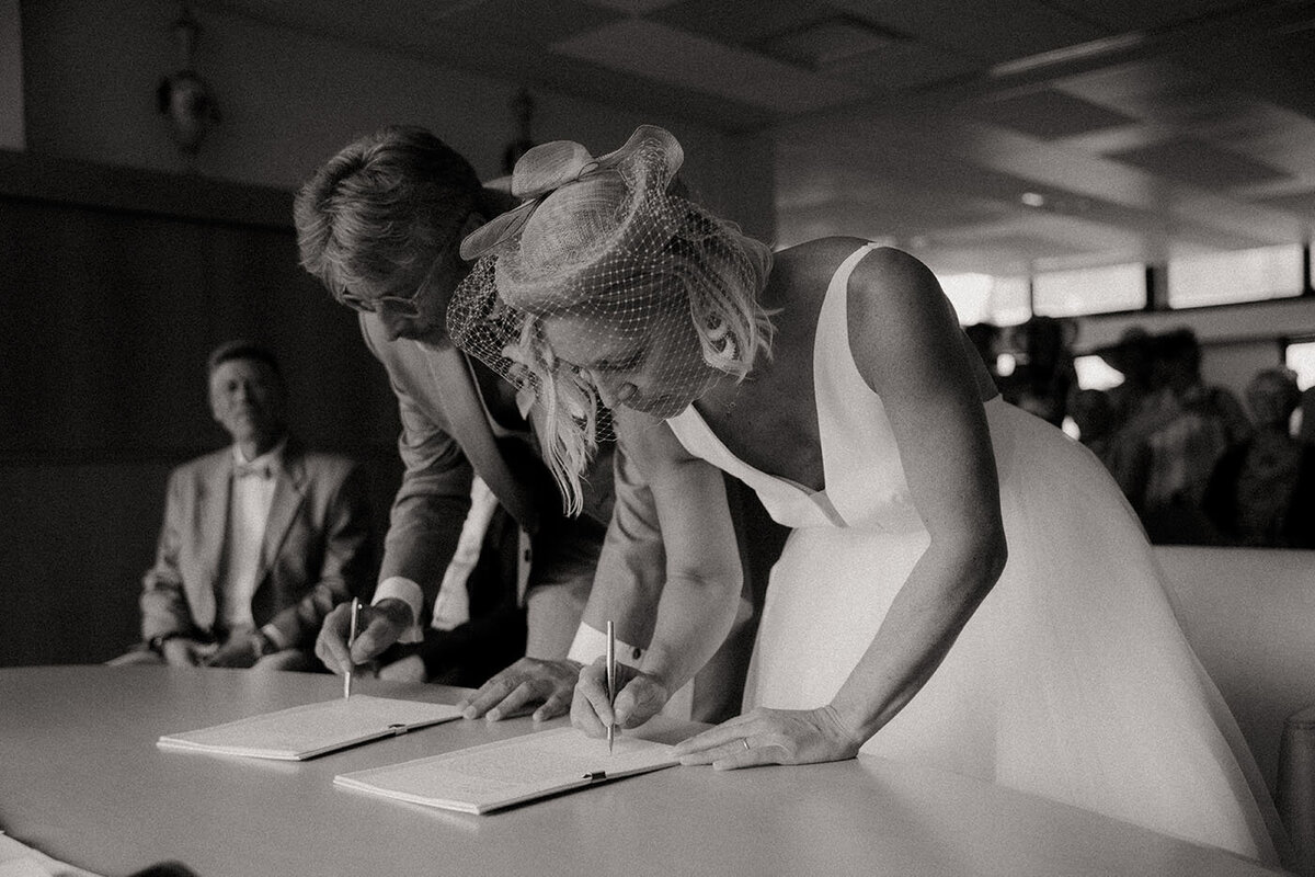 Les mariés signent le registre sous le regard des invités. Photo capturée par Kamescop, photographe et vidéaste de mariage.