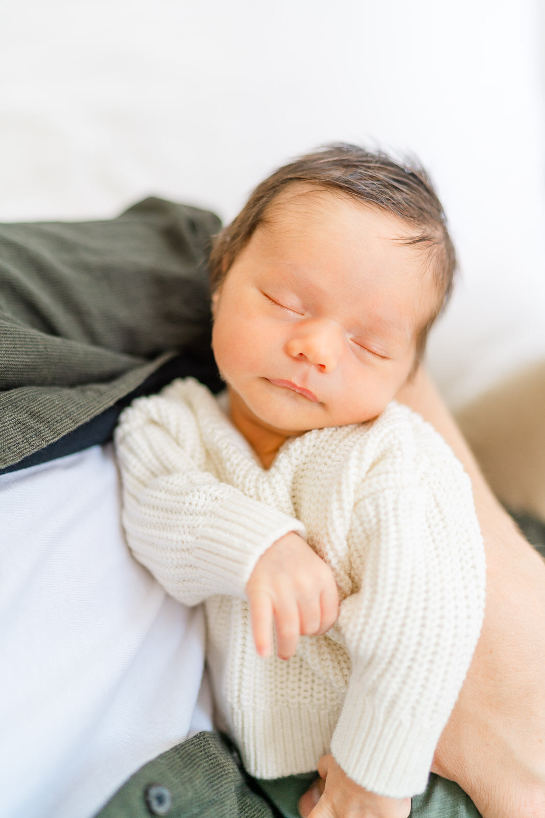a baby sleeps in his father's arms during his newborn session in Round Rock.