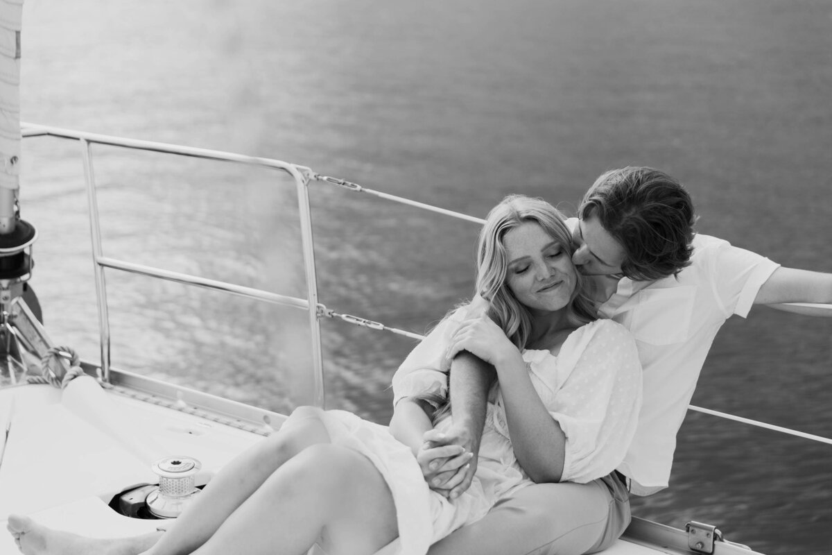 A couple sitting close together, holding hands on a sailboat 