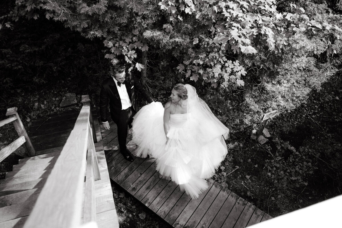 adirondack-mountain-wedding-11-aerial-view-of-couple-crossing-a-wooden-bridge-in-black-and-white-at-adirondack-mountain-wedding-jenny-fu-studio