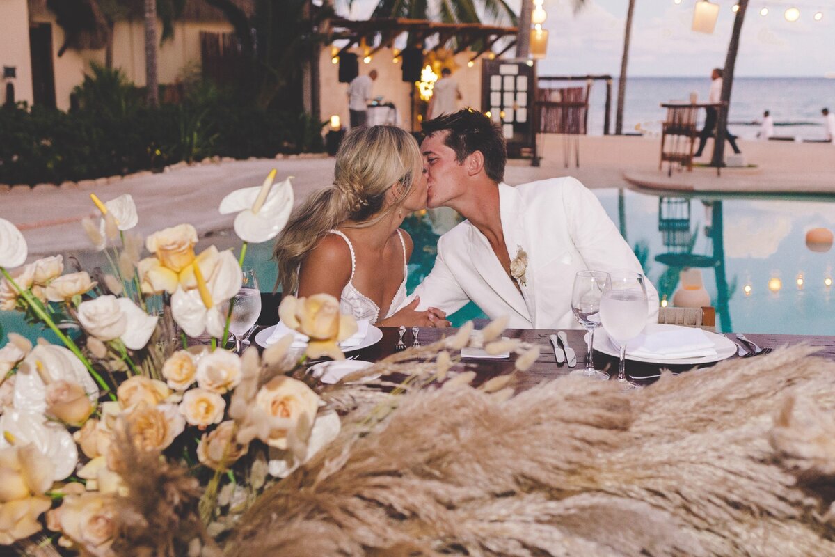Bride and groom kissing at wedding reception in Riviera Maya