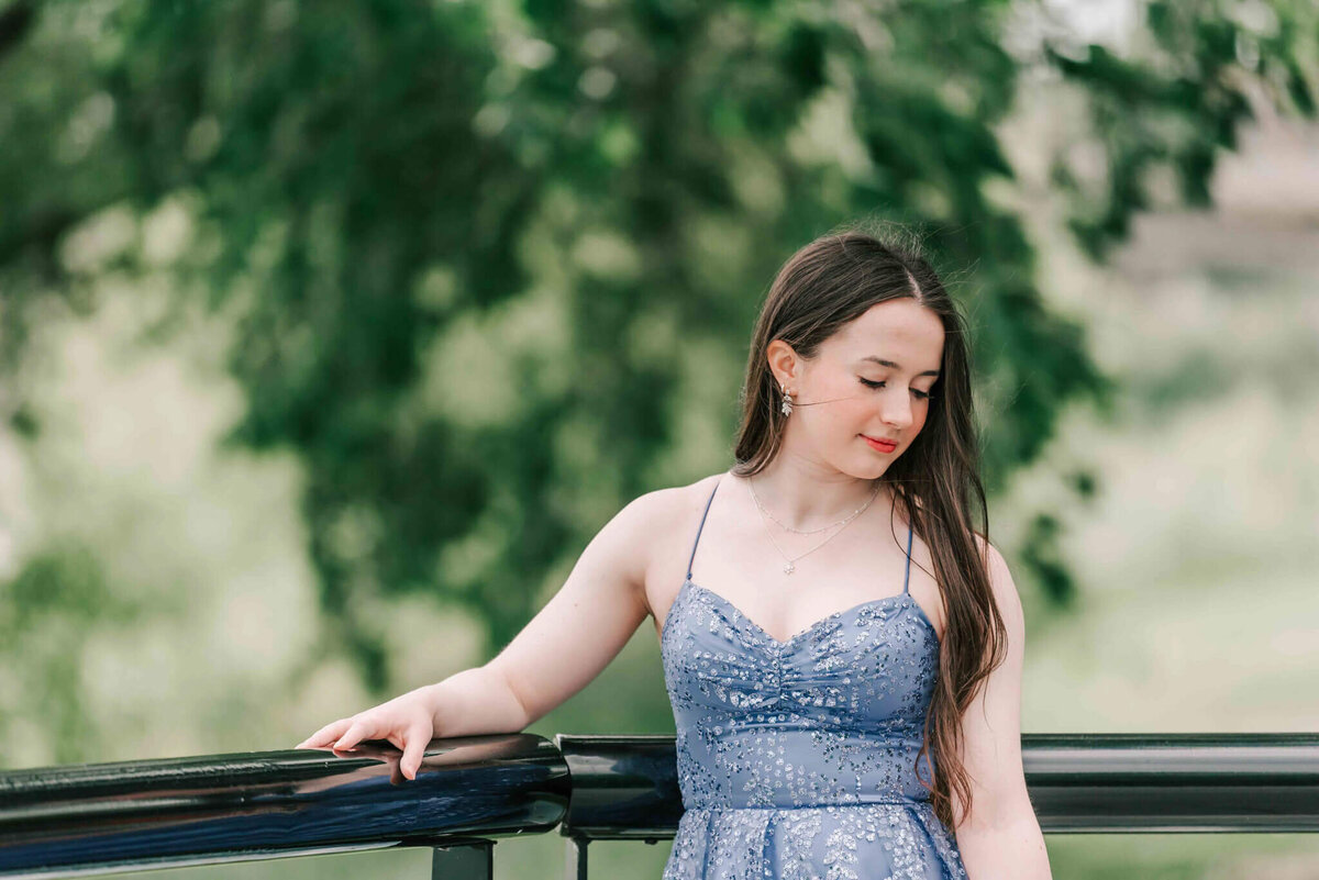 Brunette wearing a purple  dress looking down past her shoulder.