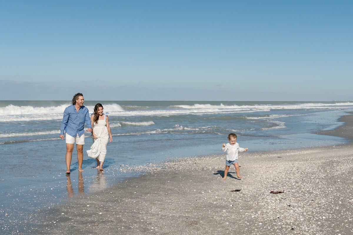 Couple with child walking along beach, taken by engagement photography florida
