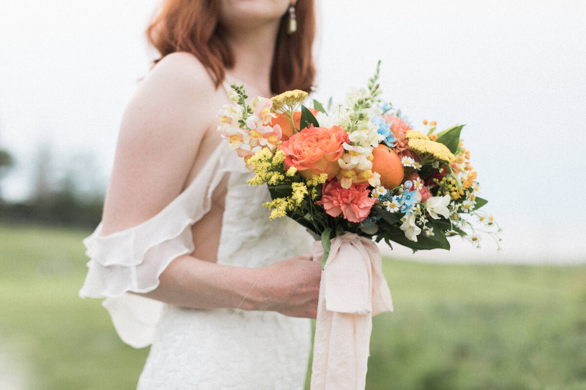 Colourful bouquet with pink, yellow, and tangerine florals by Meadow & Vine Floral, romantic Alberta wedding florist, featured on the Brontë Bride Vendor Guide.