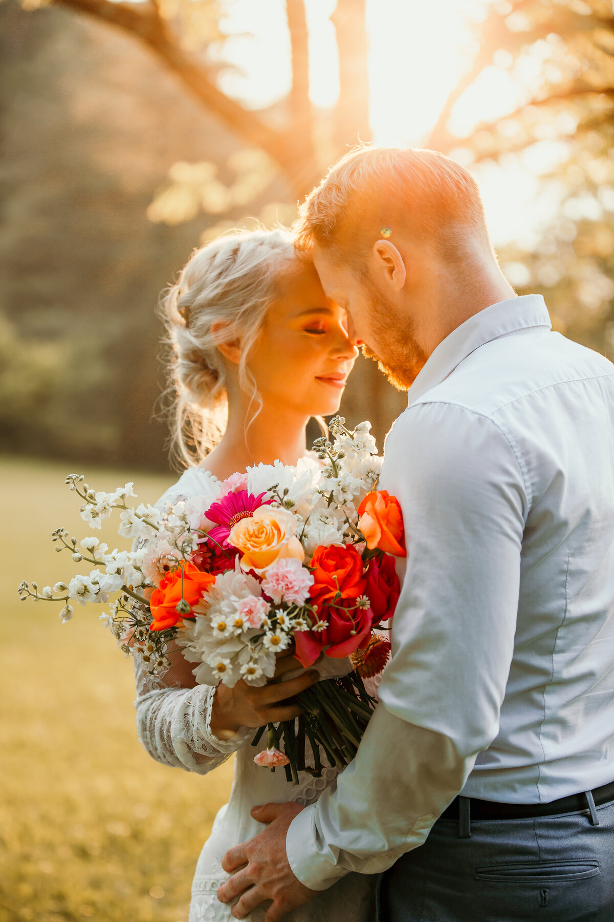 bride and groom standing forehead to forehead in sunlight