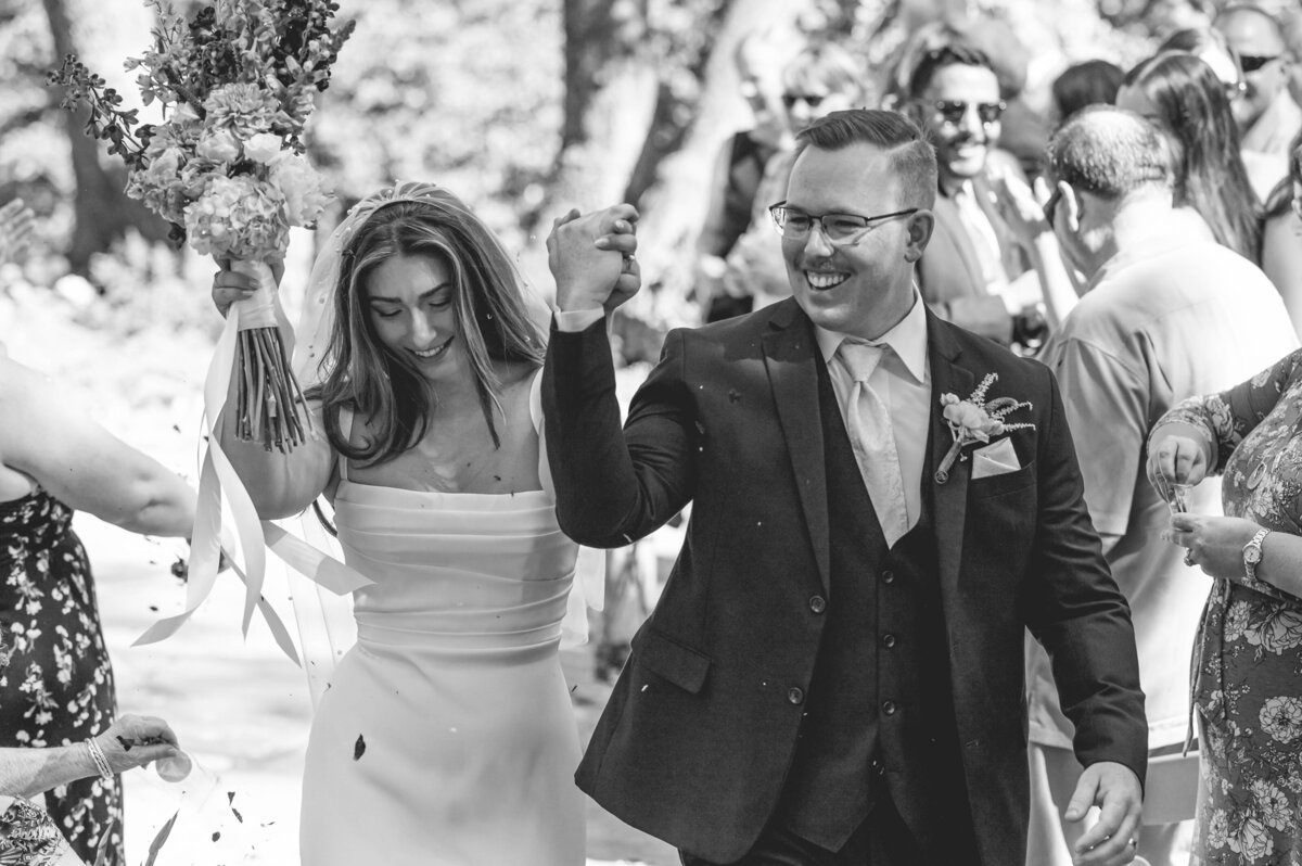 Bride cheering with her groom as they walk down the aisle