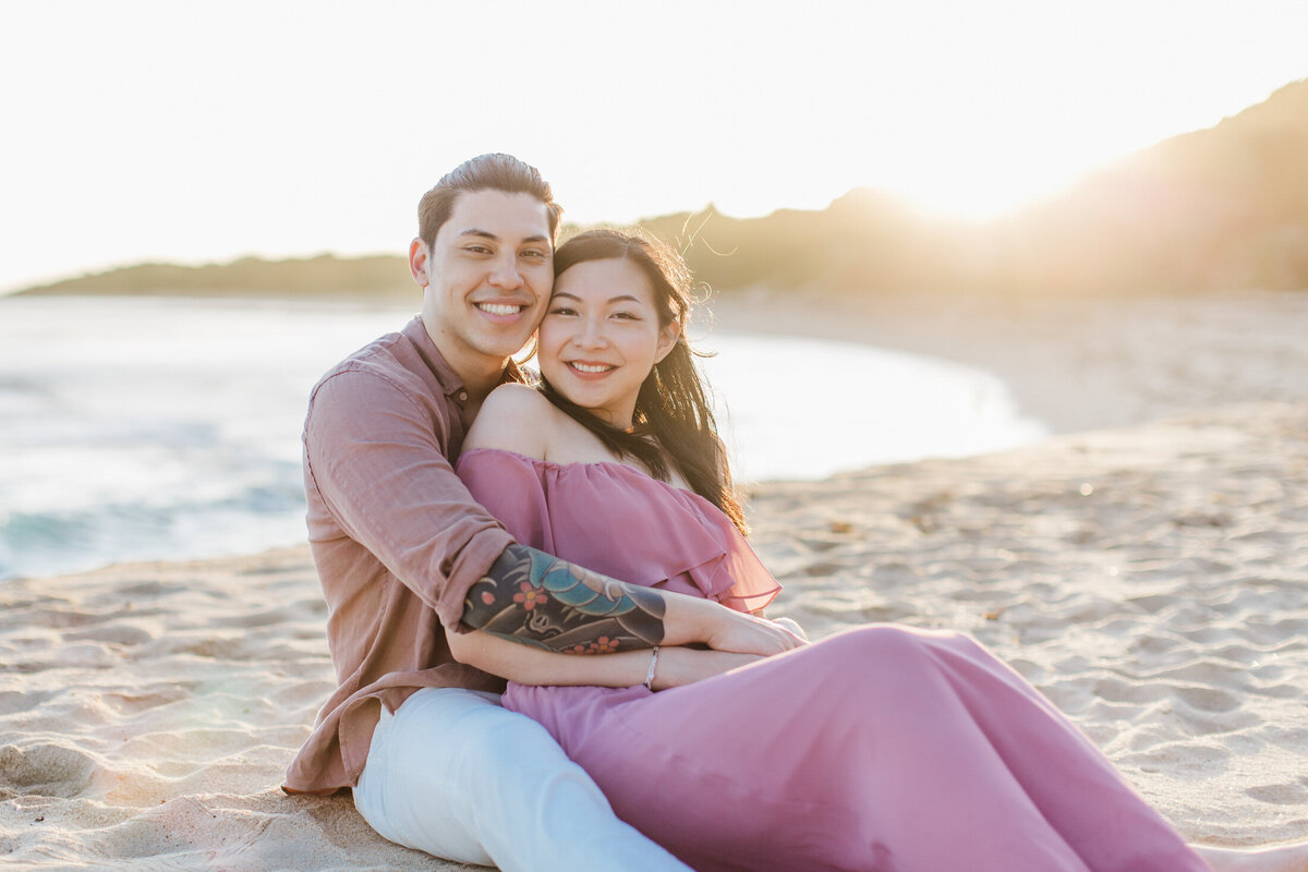 couple on beach snuggling in golden sun