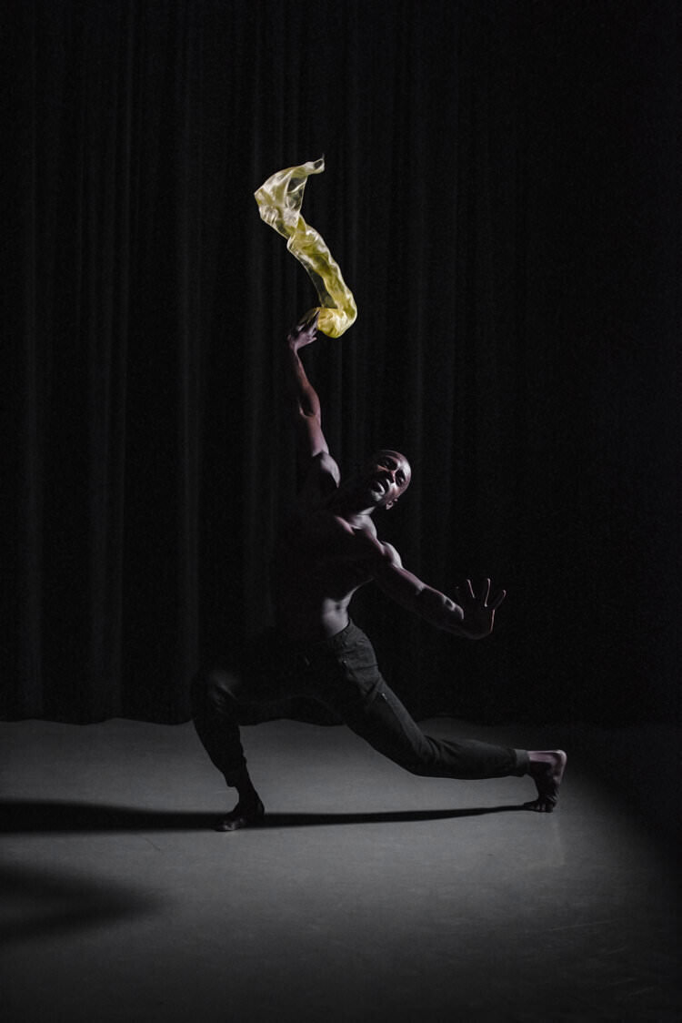 A person dancing while holding up an yellow cloth