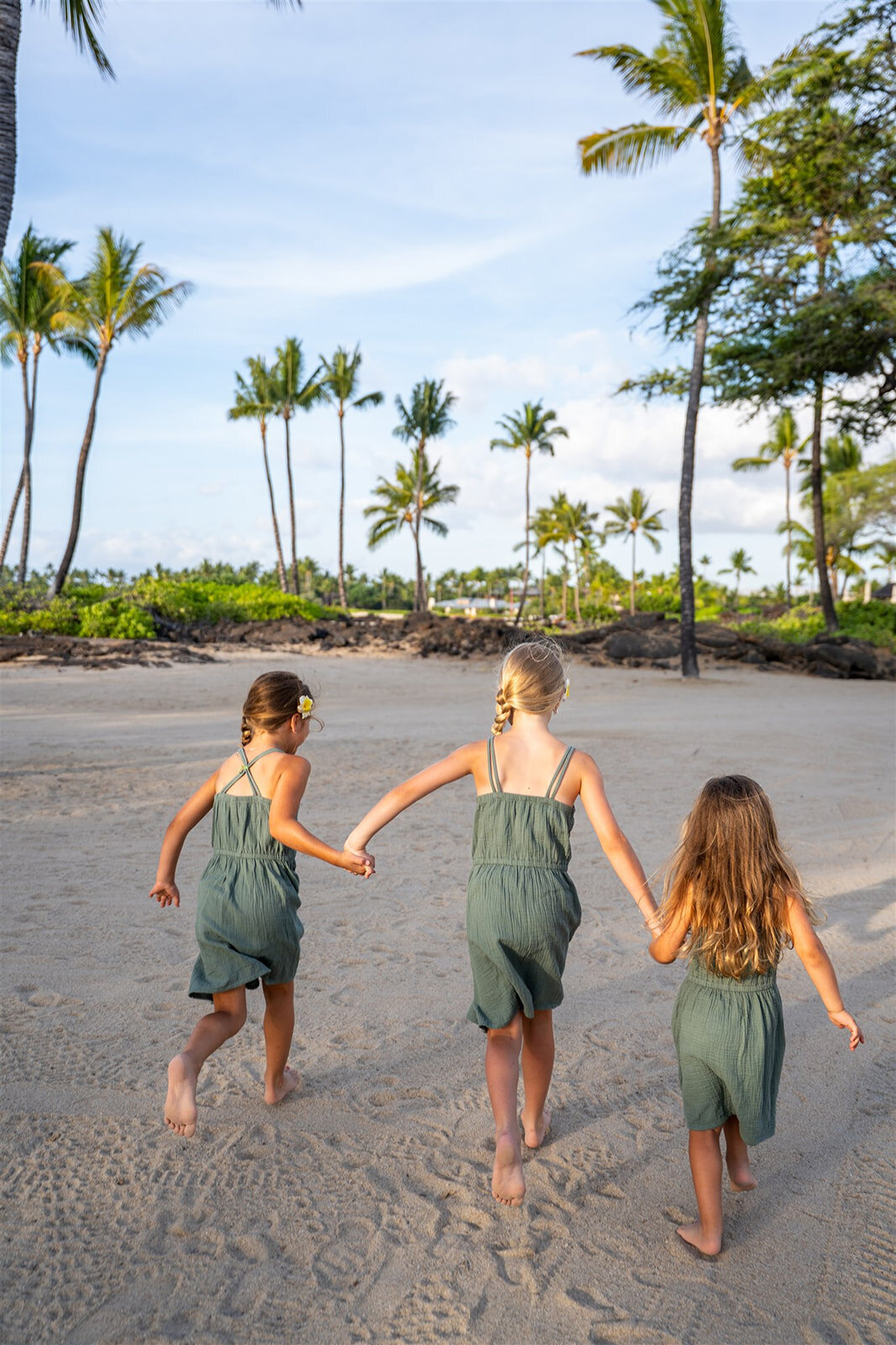 Siblings holding hands running along the beach, by the best big island family photographers

