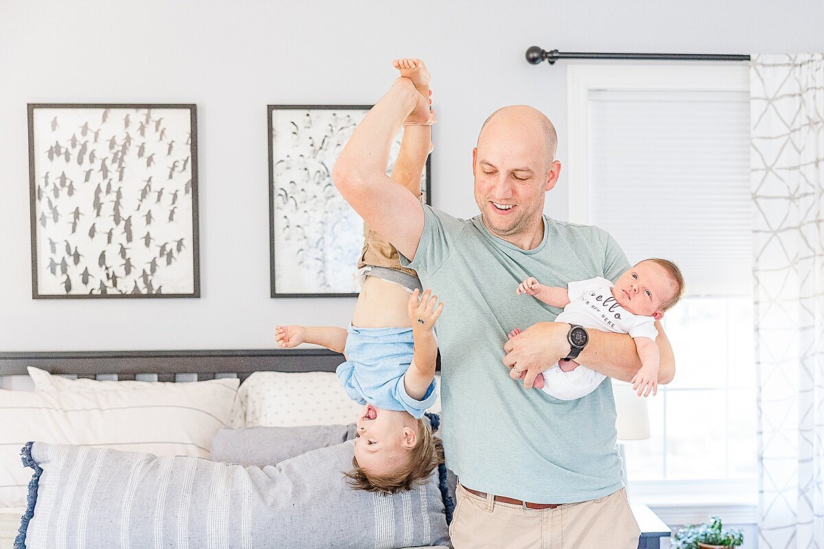 dad holds baby and older sun  dung in-home newborn photo session with Sara Sniderman Photography in metro west Boston  Massachusetts