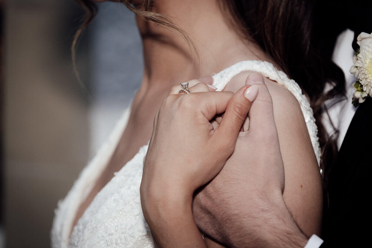 Edinburgh wedding photographer, a couple hold hands tightly while resting their hands on the brides left shoulder.